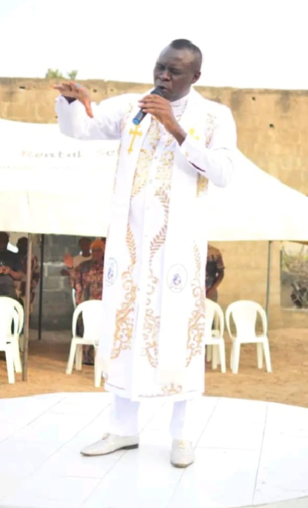 Apostle Prof. E. C. Ejiofor preaching in a white and gold embroidered robe