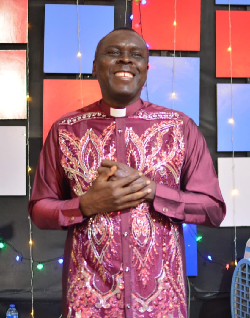 Apostle Prof. E. C. Ejiofor preaching in a maroon robe with ornate embroidery at Praiseland Royal Springs Int'l Church