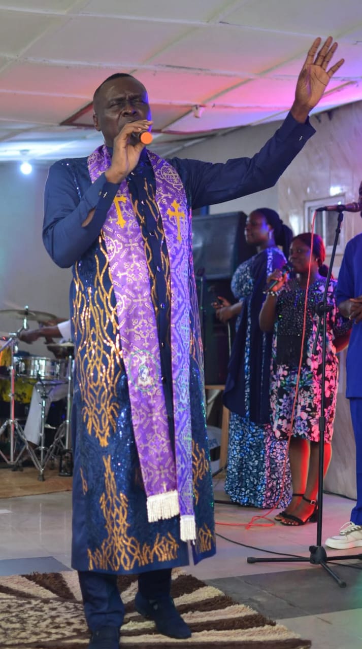 Apostle Prof. E. C. Ejiofor worshipping in a purple and gold stole at Praiseland Royal Springs Int'l Church