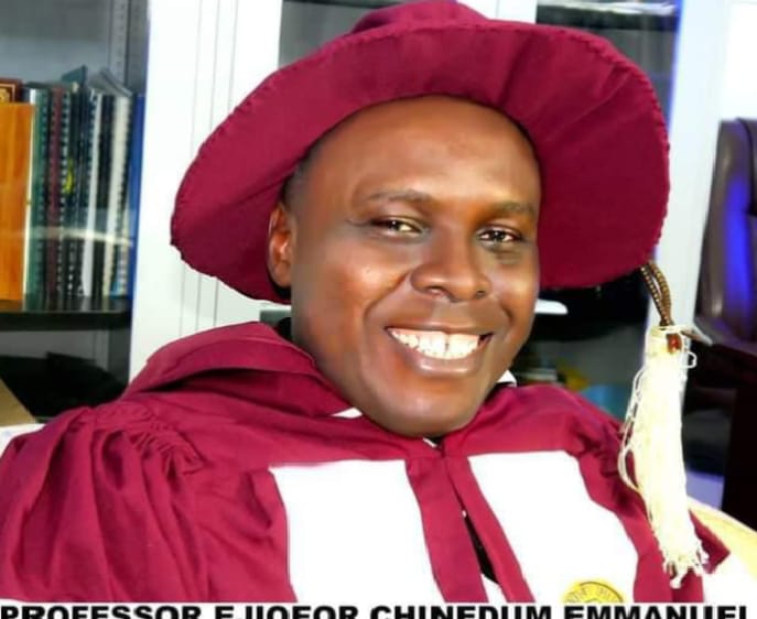 Apostle Prof. E. C. Ejiofor in maroon academic regalia with a tam and tassel, smiling — a portrait of the General Overseer of Praiseland Royal Springs Int'l Church