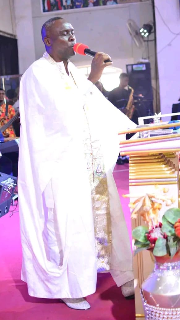 Apostle Prof. E. C. Ejiofor ministering in a white and gold robe at Praiseland Royal Springs Int'l Church