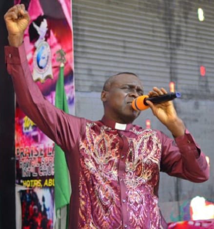 Apostle Prof. E. C. Ejiofor ministering with raised hand and microphone